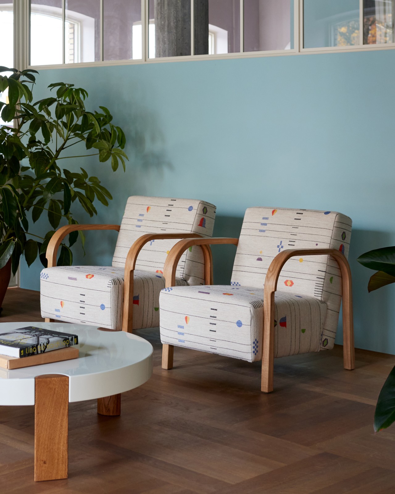 Two Arch Lounge Chairs in patterned upholstery beside a white coffee table against a blue wall