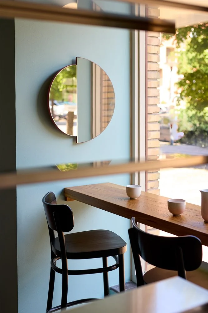 RAE Mirror O60 in a café setting above a wooden counter with bar stools