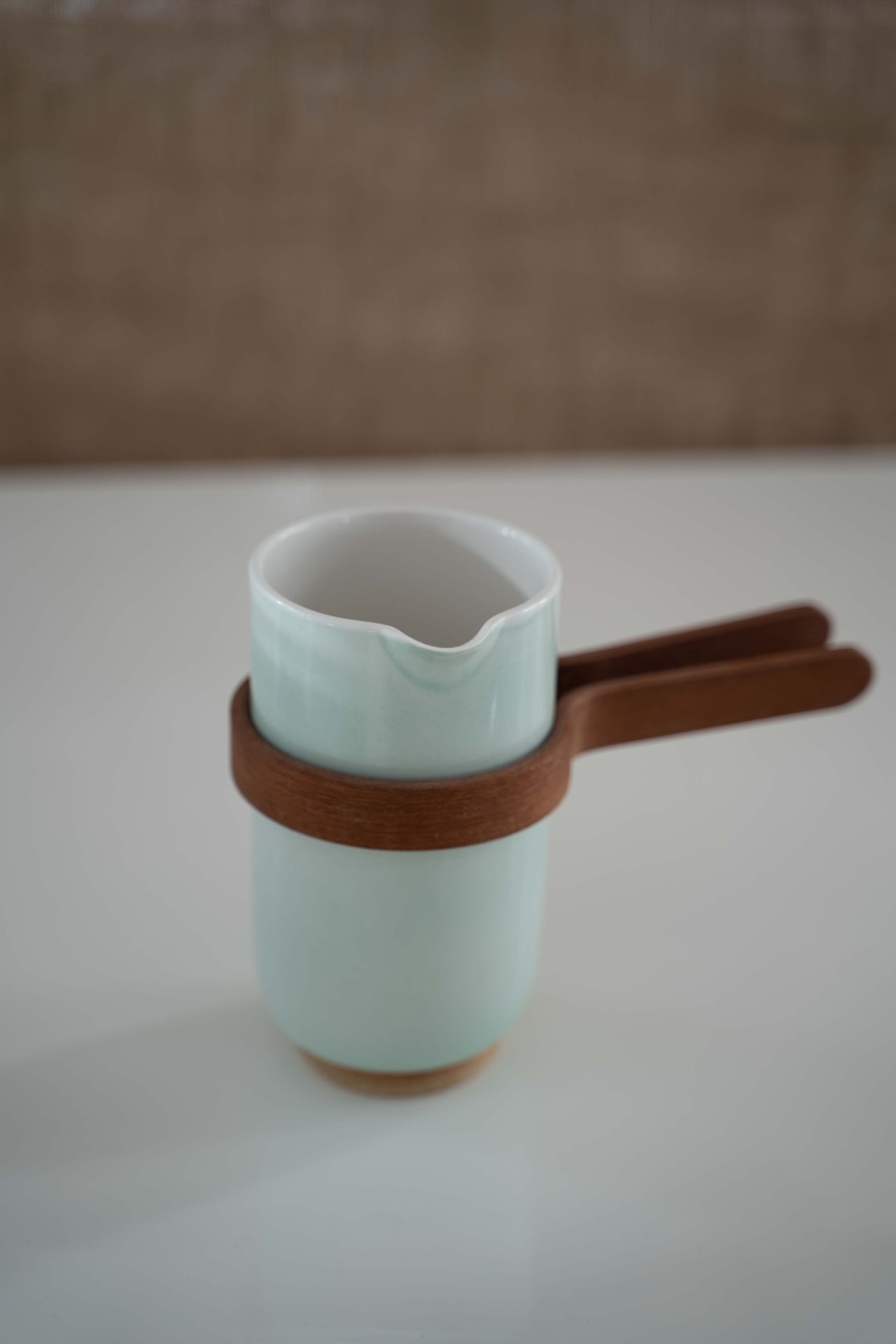 Mazo pitcher in light blue glaze with oak handle on a white table