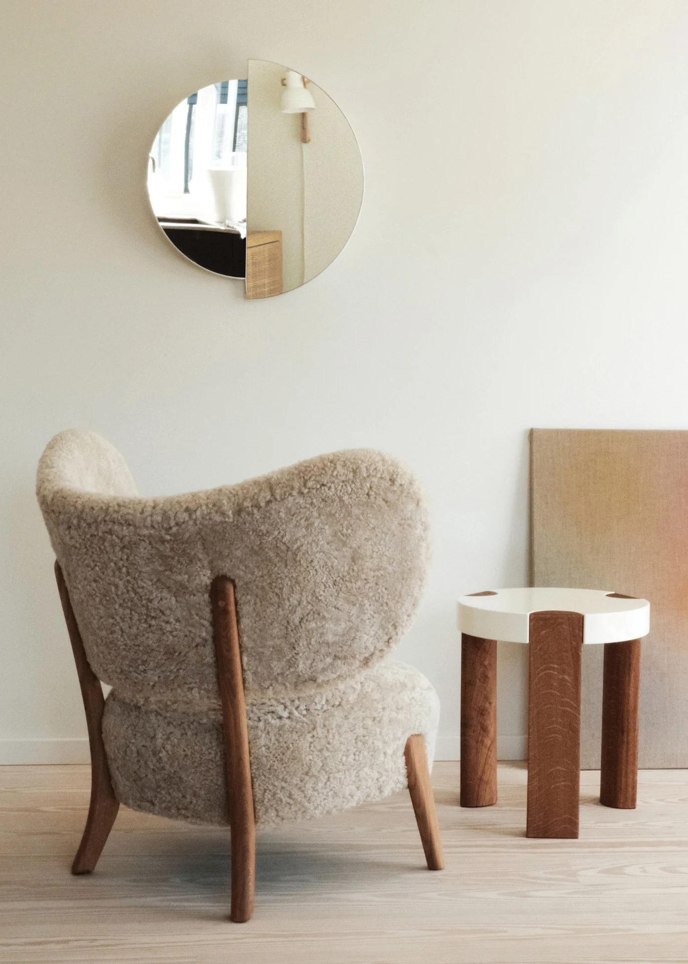 TMBO Lounge Chair in cream sheepskin seen from behind with a round RAE Mirror and a white side table