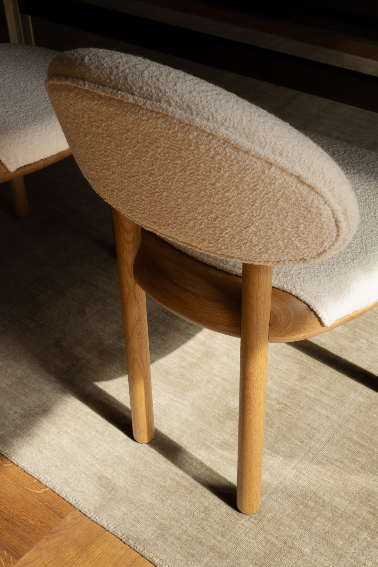 Detail of a MAG Dining Chair with bouclé seat on oak legs in sunlight