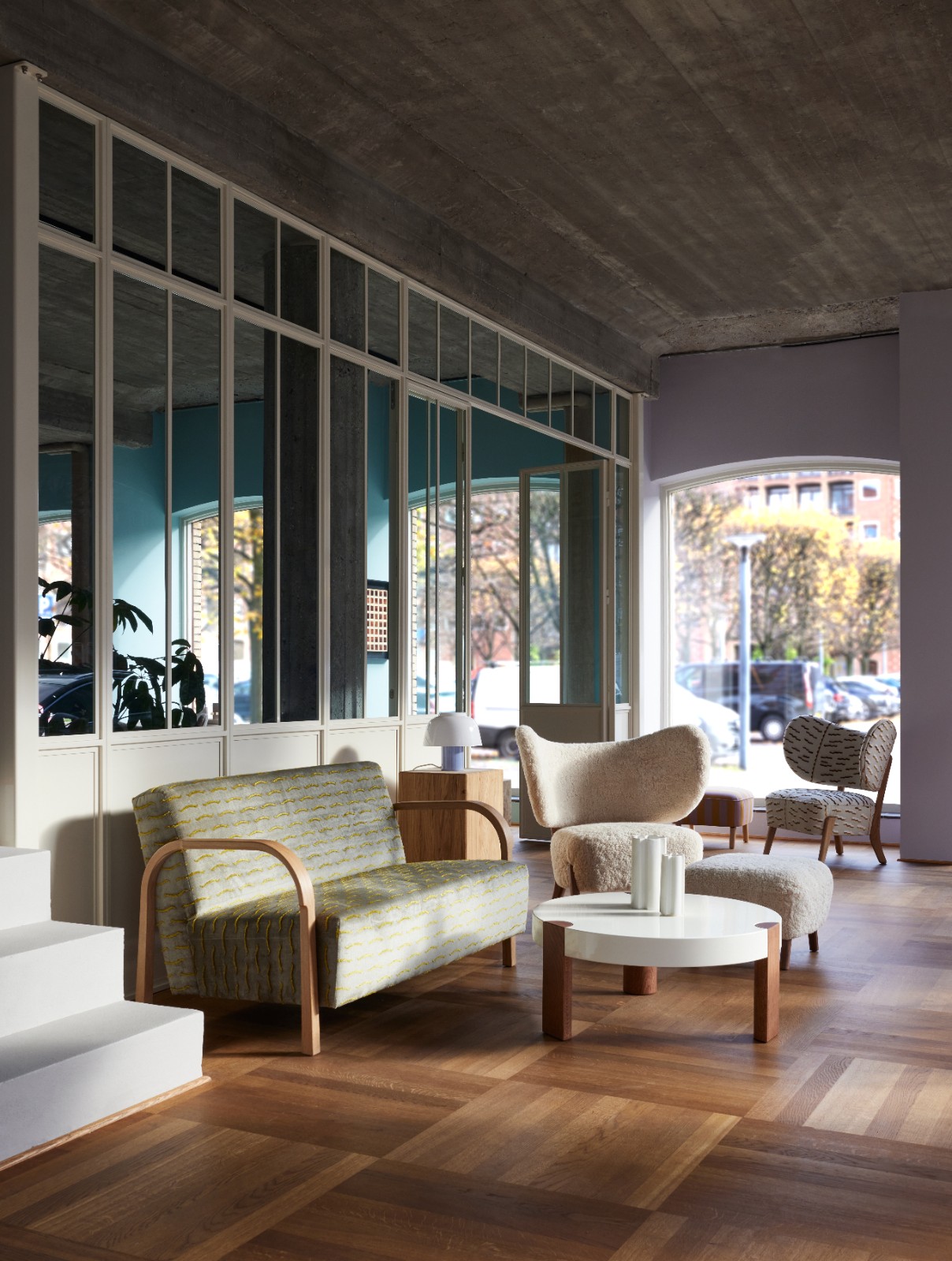 ARCH 2 Seater Sofa in yellow patterned upholstery in the Mazo showroom with sheepskin lounge chairs