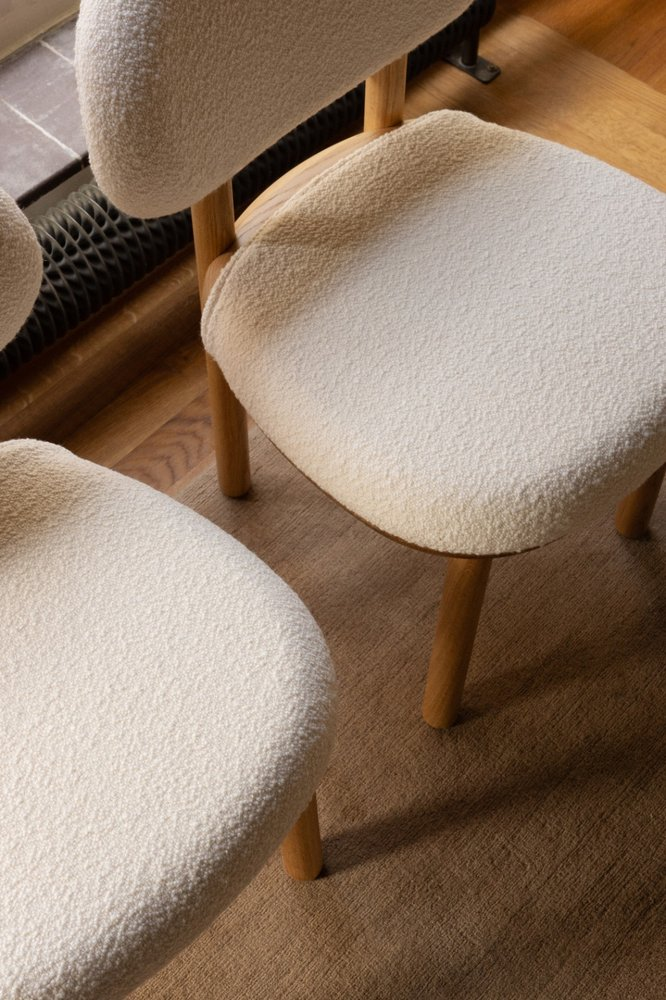 Detail of two MAG Dining Chairs with white bouclé seats on oak legs