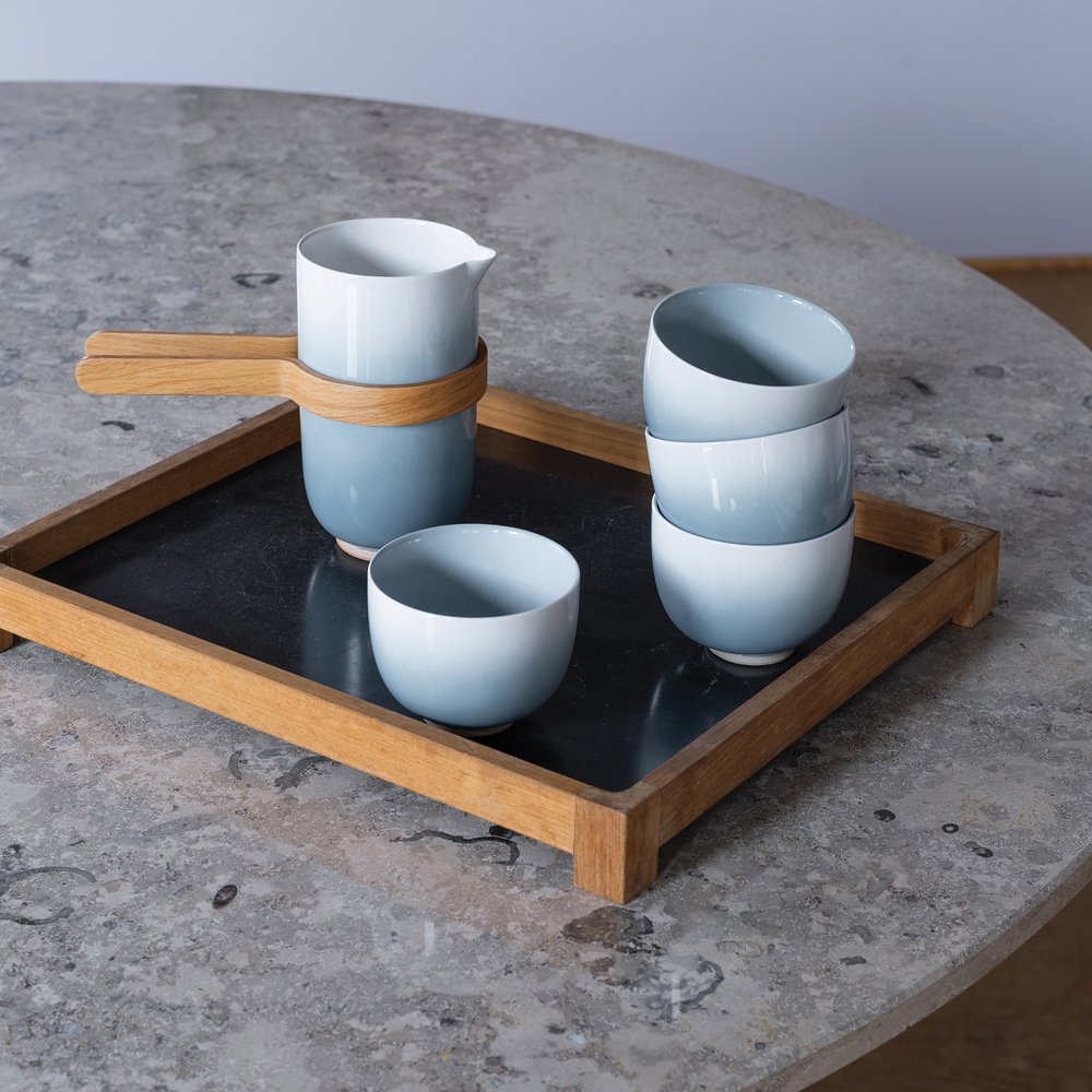 Blue gradient cups, teapot and tray with oak handles on a stone table