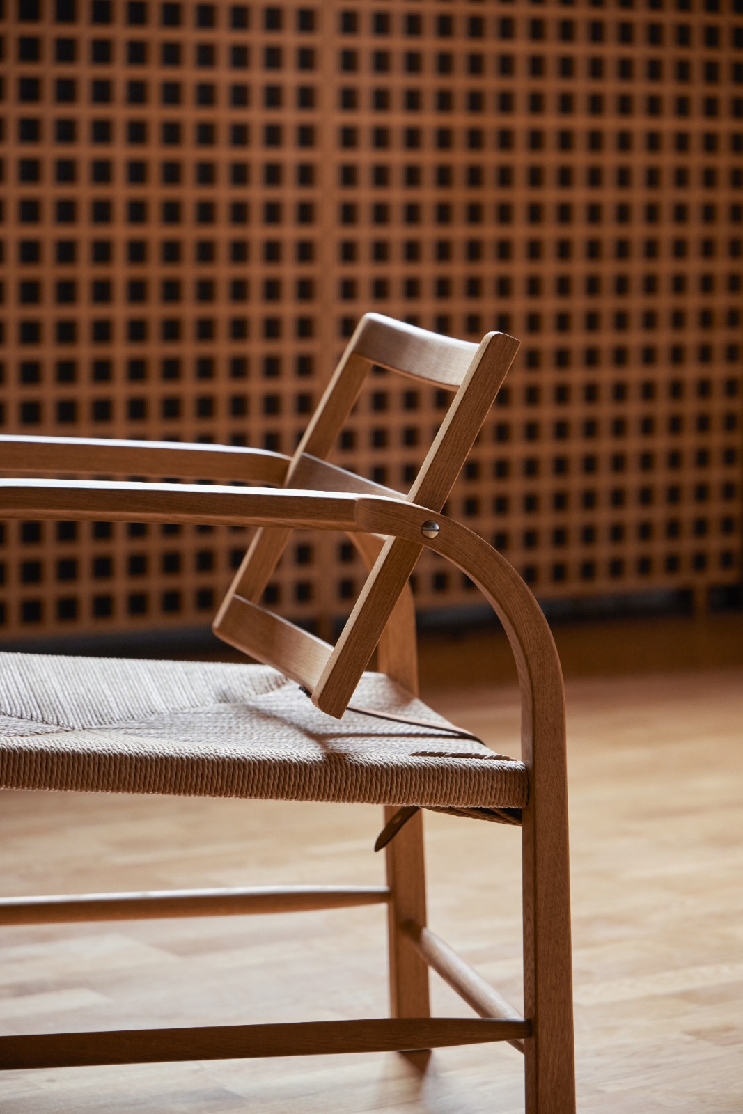 Detail of the oak frame and woven seat in front of a lattice screen