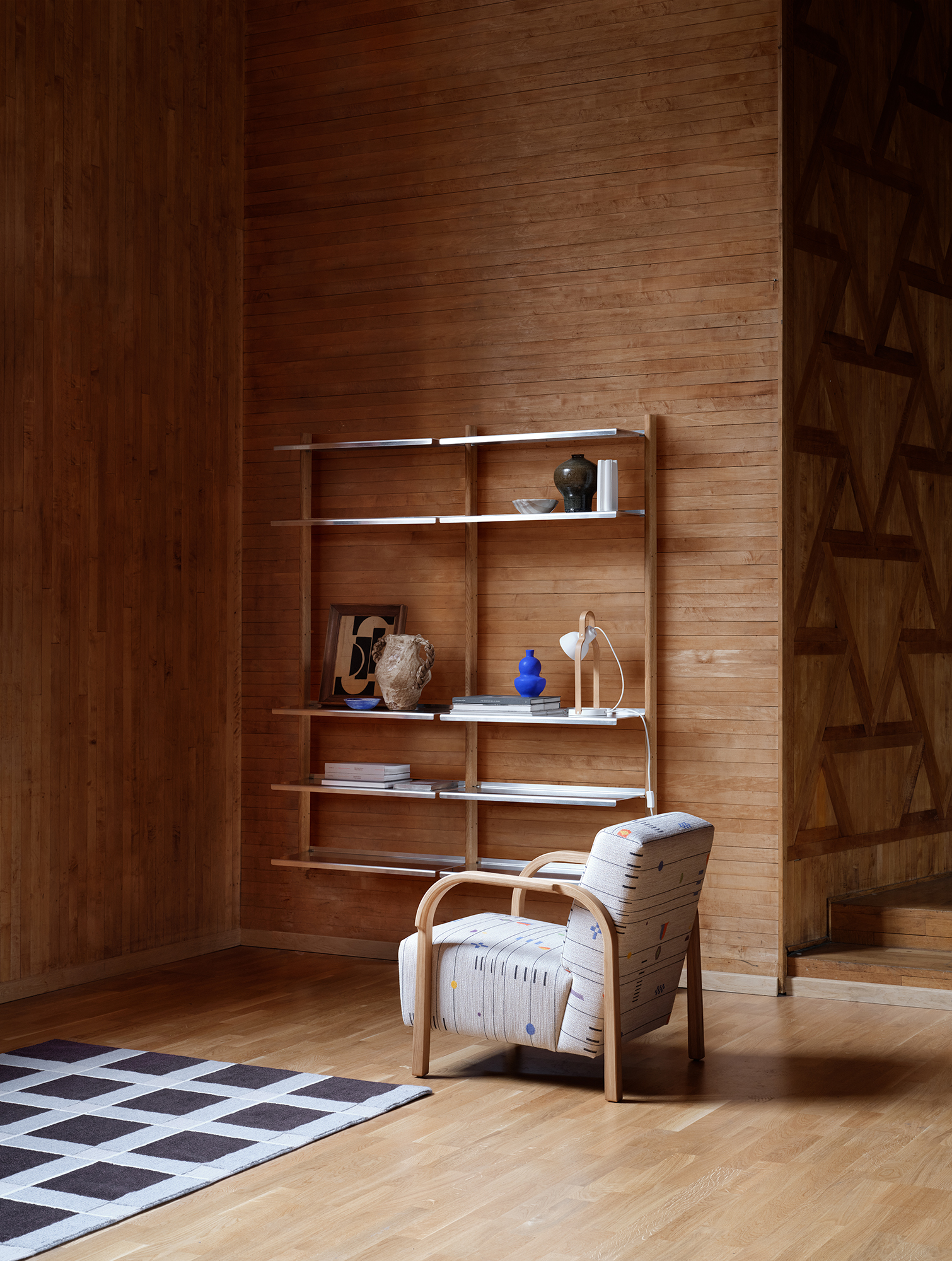 Arch Lounge Chair beside a MOD Shelving System against a wooden wall