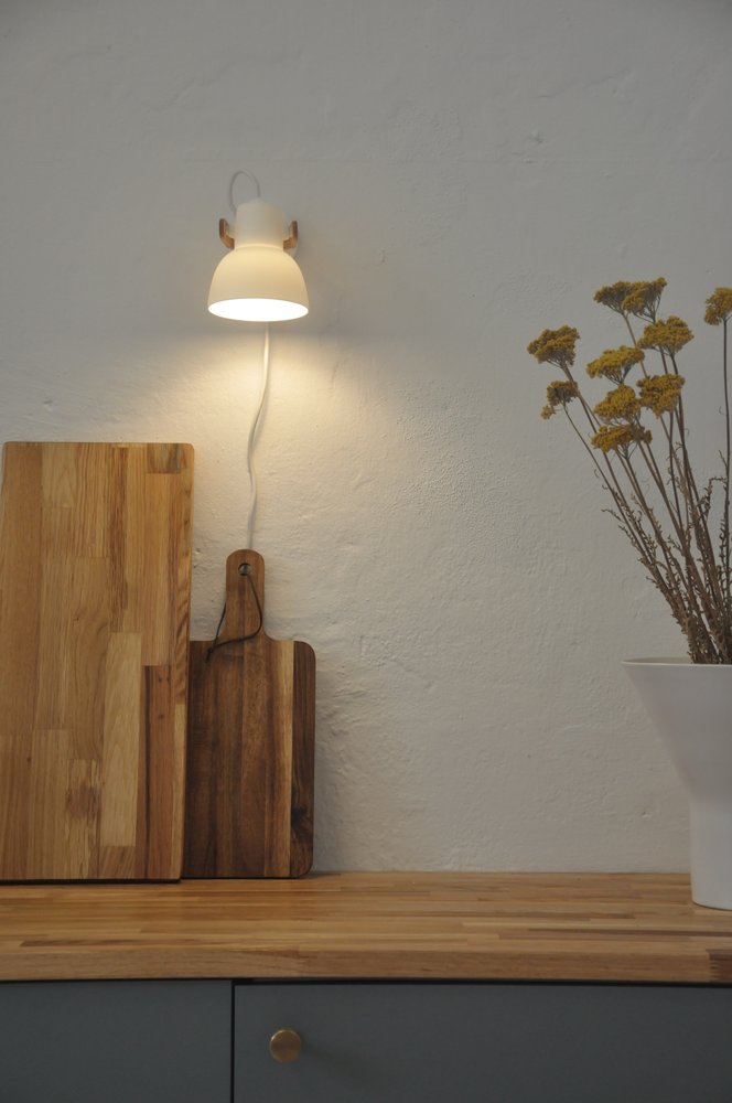 16PLUS Wall Lamp glowing above cutting boards on an oak kitchen counter
