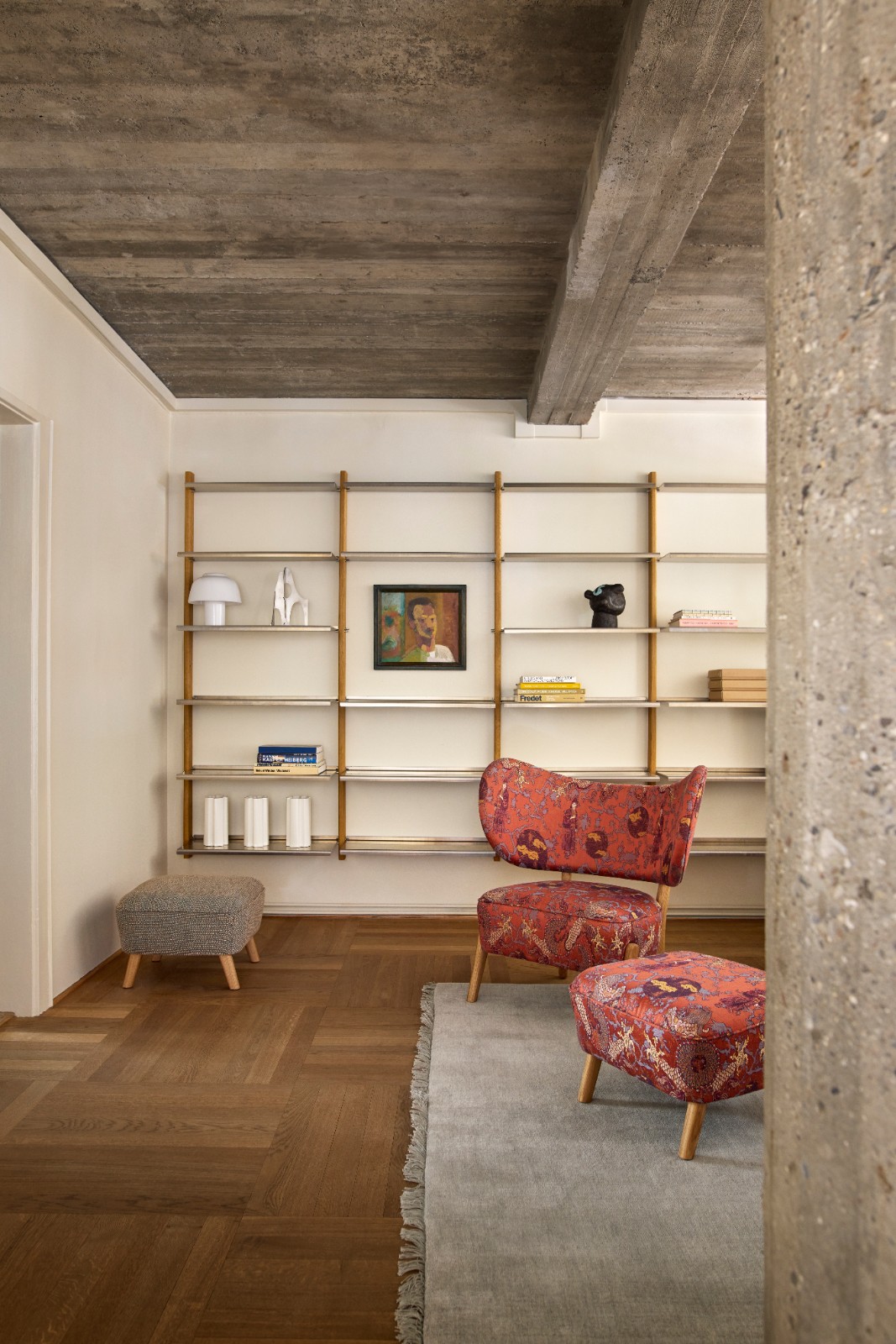 MOD Shelving System in oak and aluminium styled with books and art behind red patterned lounge chairs