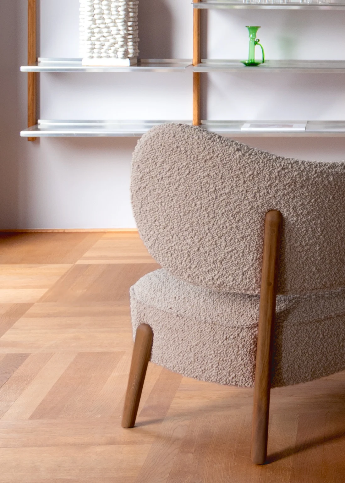Detail of the TMBO Lounge Chair in taupe bouclé in front of aluminium and oak shelving