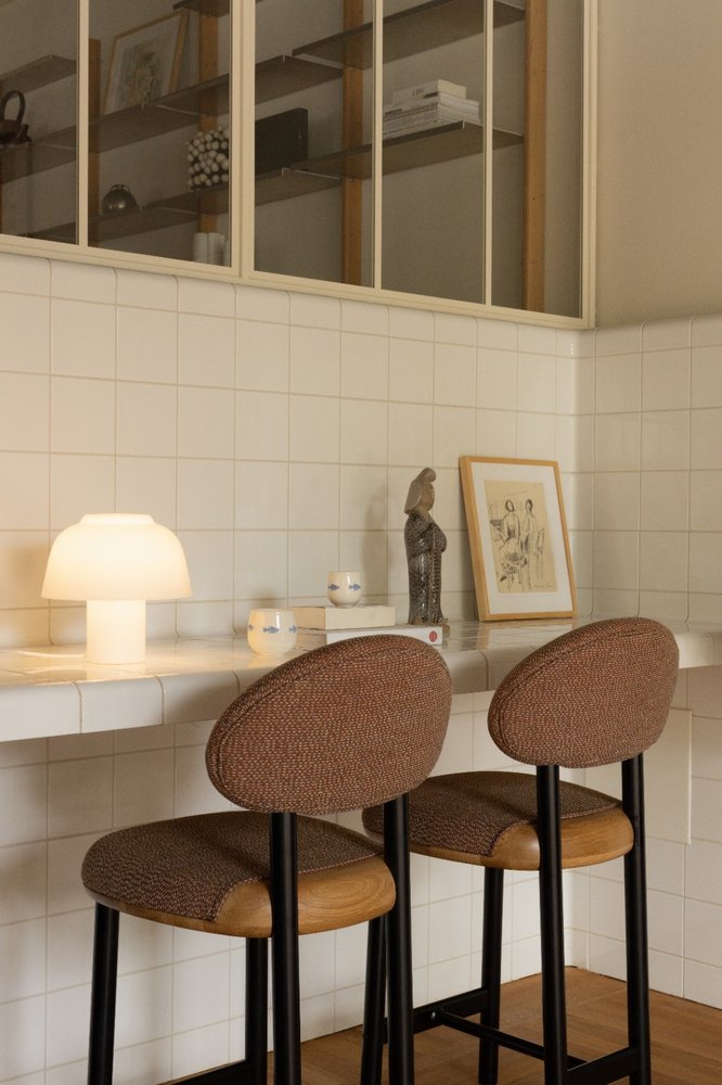 YUKI Lamp glowing on a tiled kitchen counter beside two brown upholstered barstools