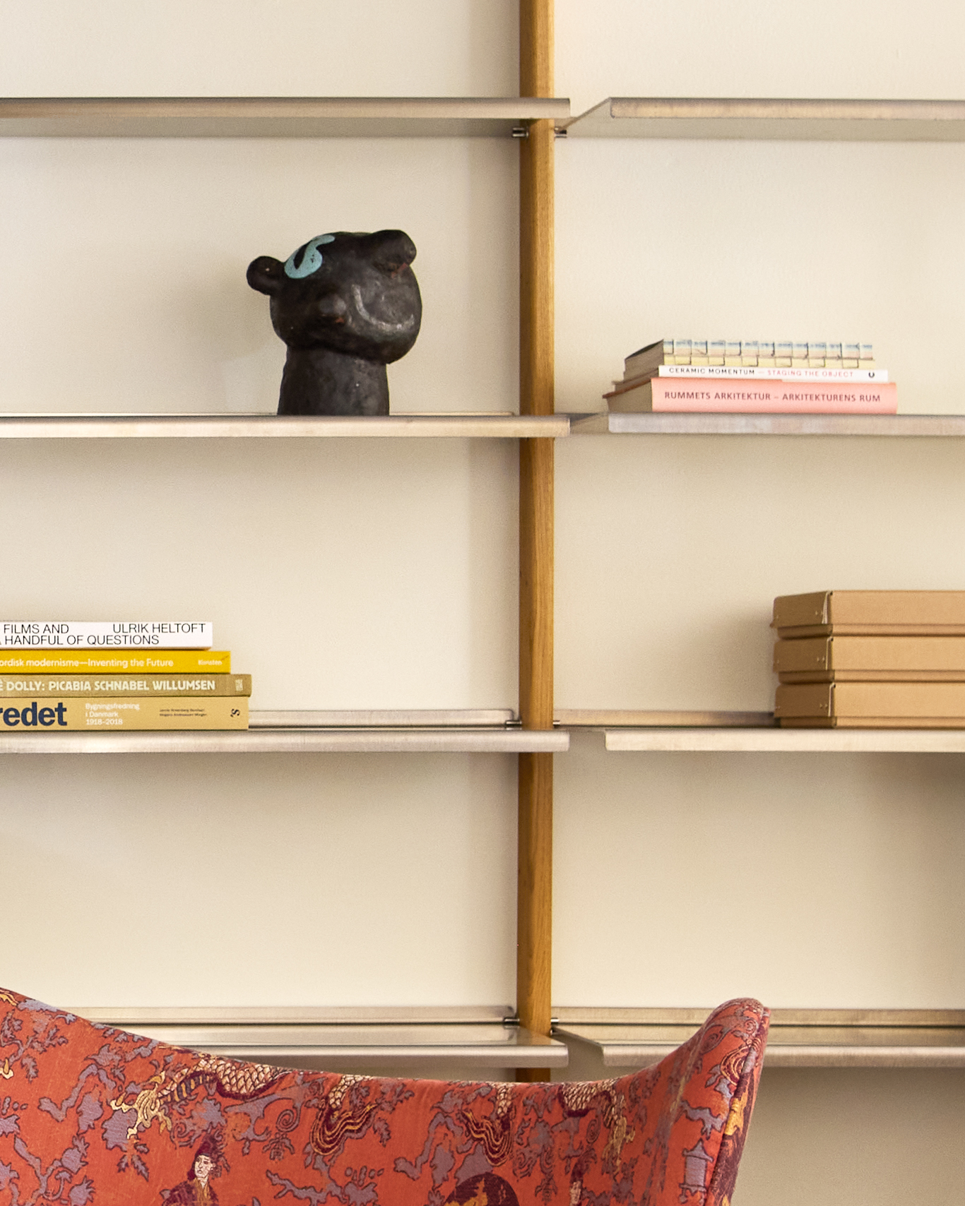 Detail of the MOD Shelving System in oak and aluminium with a black sculpture, books and boxes