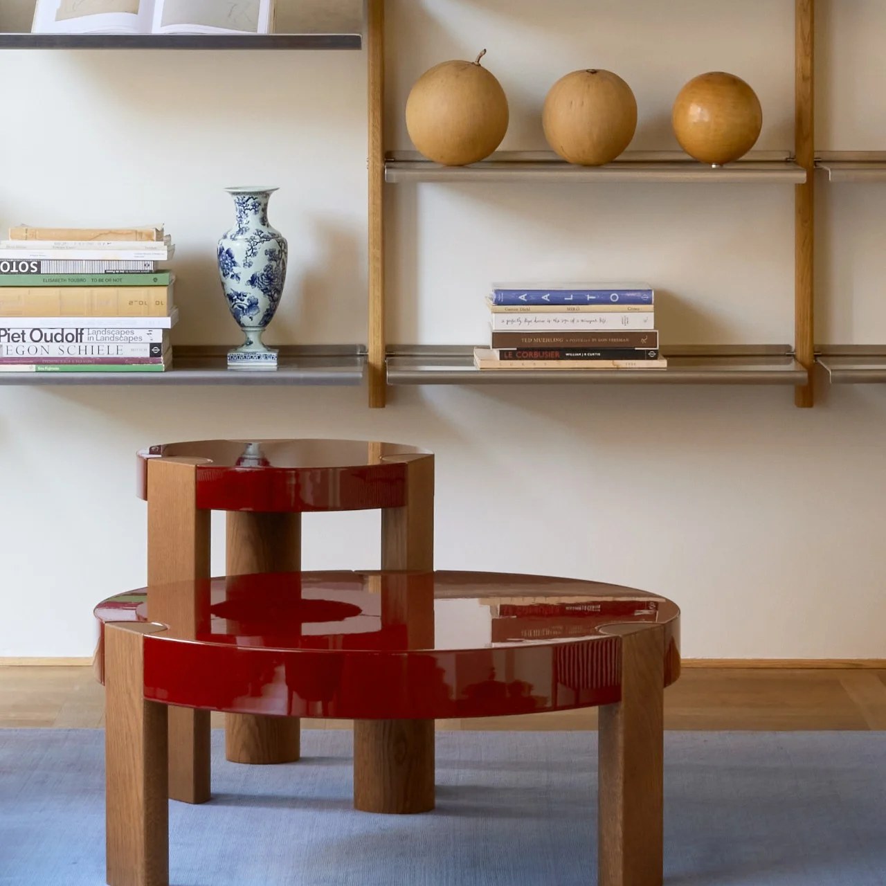 Two FER Coffee Tables in glossy red with oak legs in a living room with a blue vase