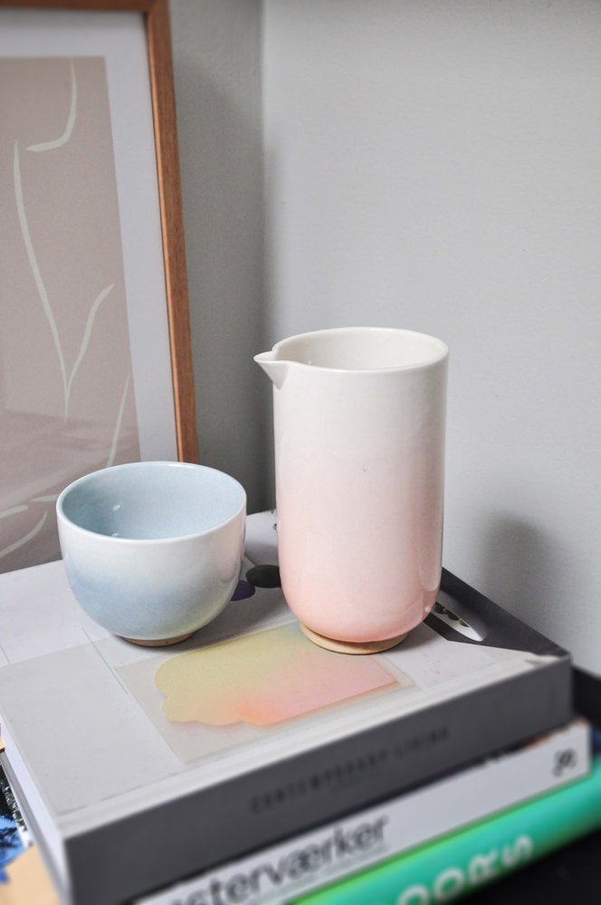 Pink gradient teapot and small blue cup on stacked design books
