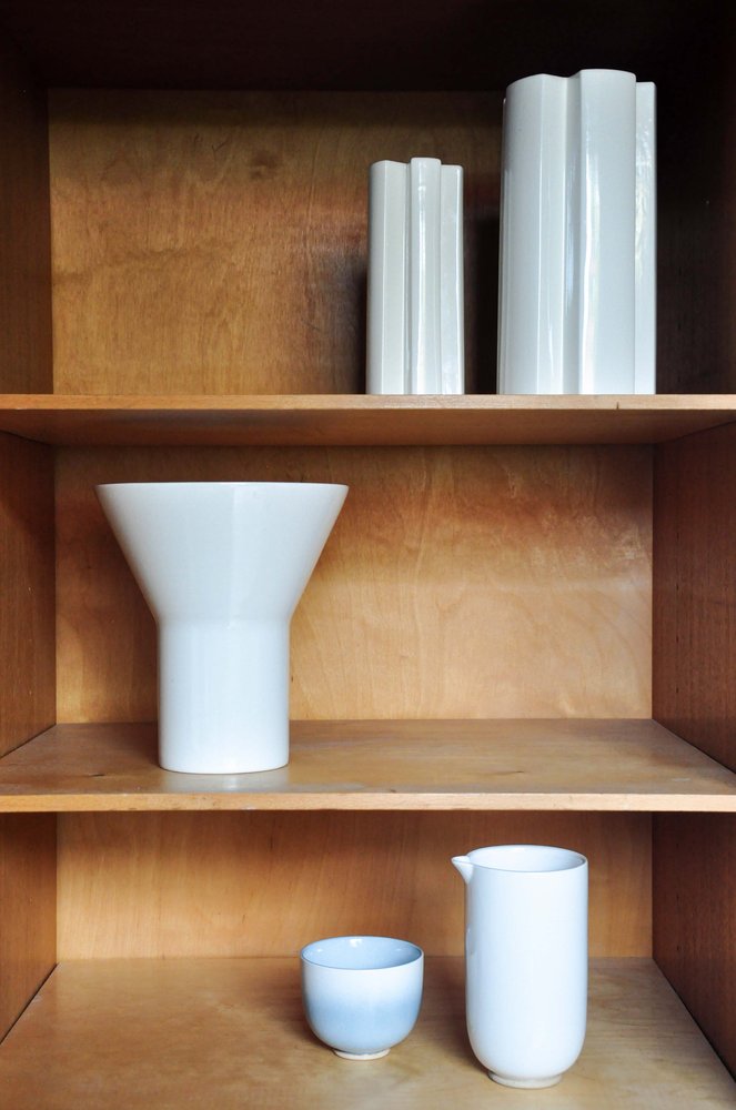 White vases, jug and blue cup arranged on wooden shelves