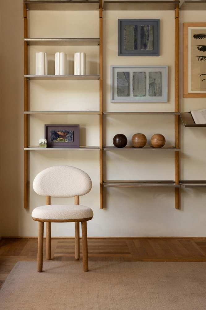 White bouclé MAG Dining Chair in front of a MOD Shelving System with framed artwork