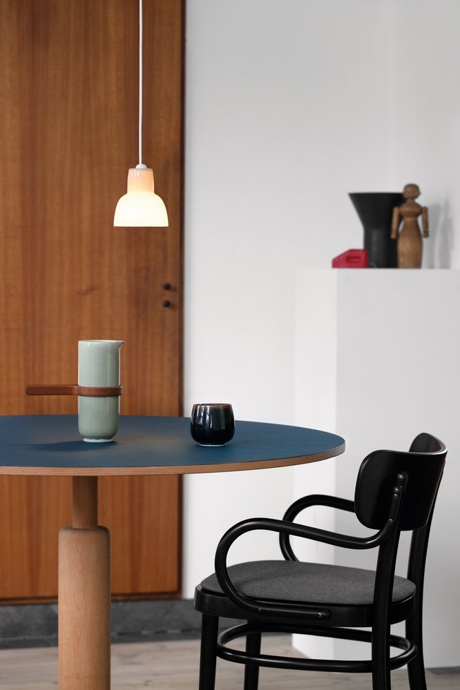16PLUS Pendant in olive above a round blue table with a black chair in a wood-panelled interior