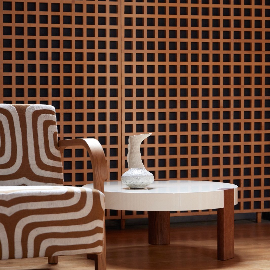 FER Coffee Table in white beside a striped armchair in front of a wooden grid wall