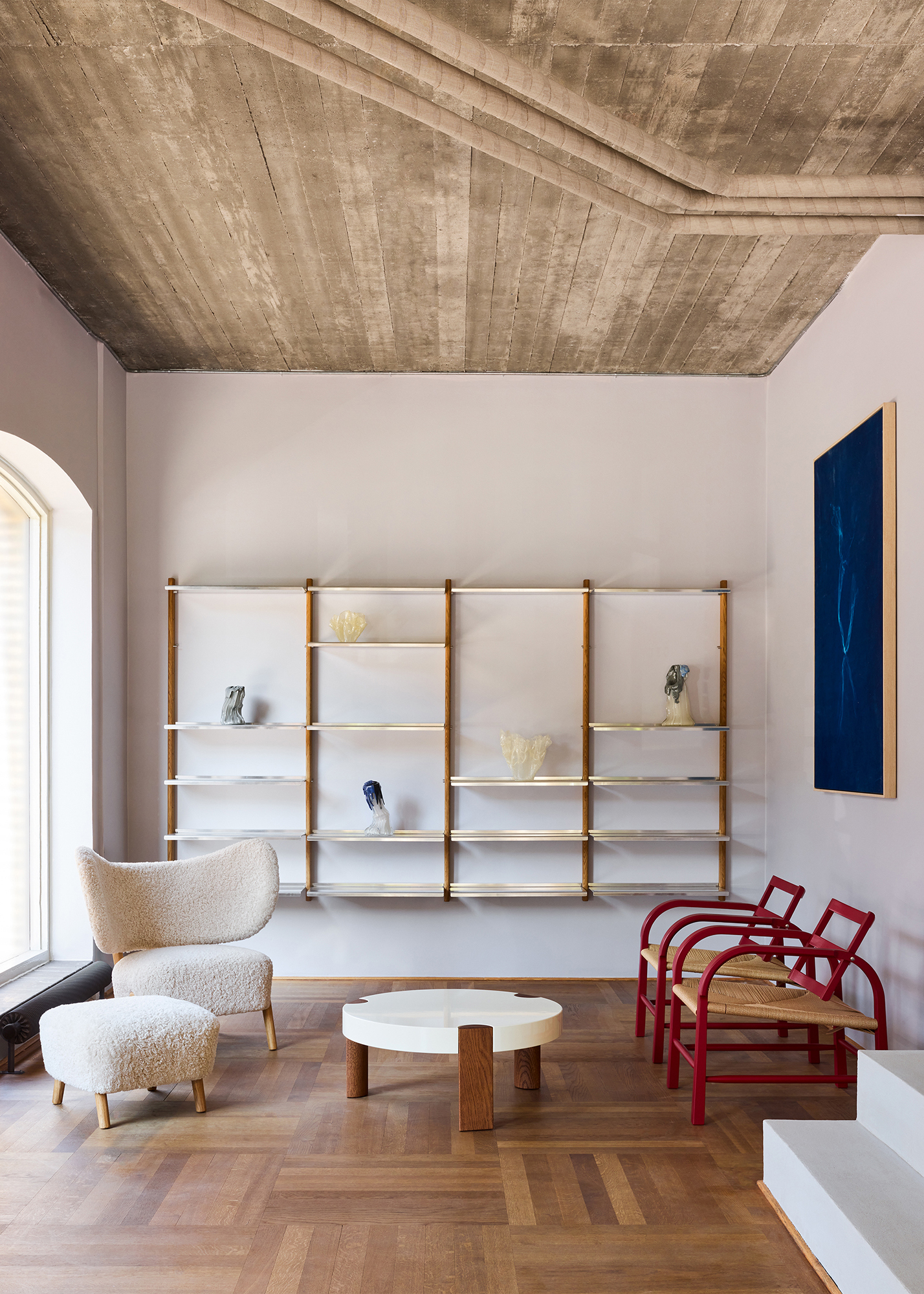 TMBO Lounge Chair with pouf in cream sheepskin in the Mazo showroom with a white FER coffee table and red chairs