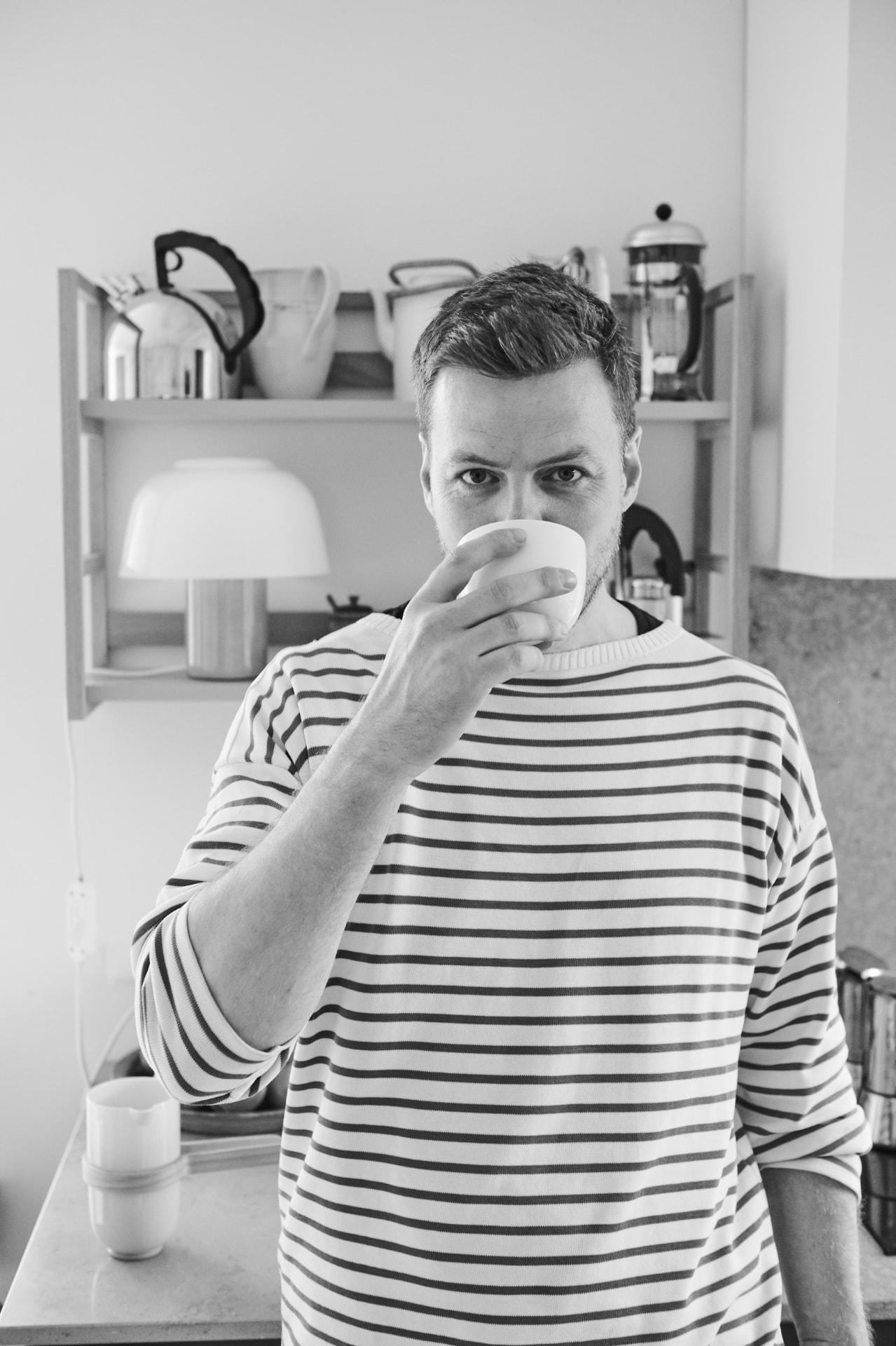 Magnus Sangild drinking from a ceramic cup in his kitchen