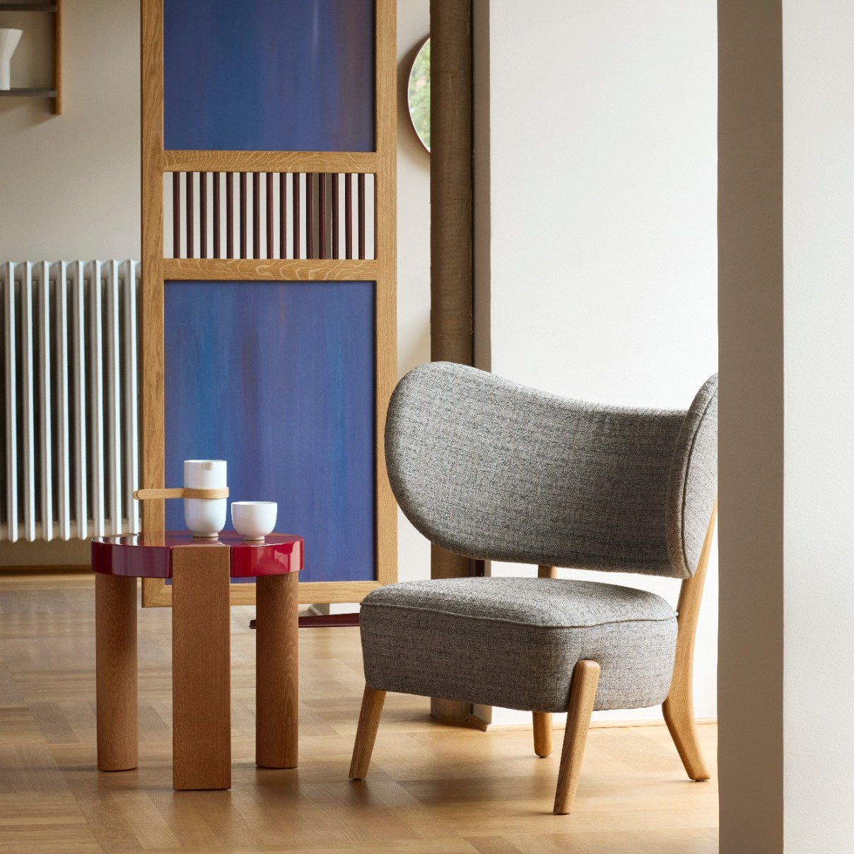 FER Side Table in glossy red with oak legs beside a grey lounge chair