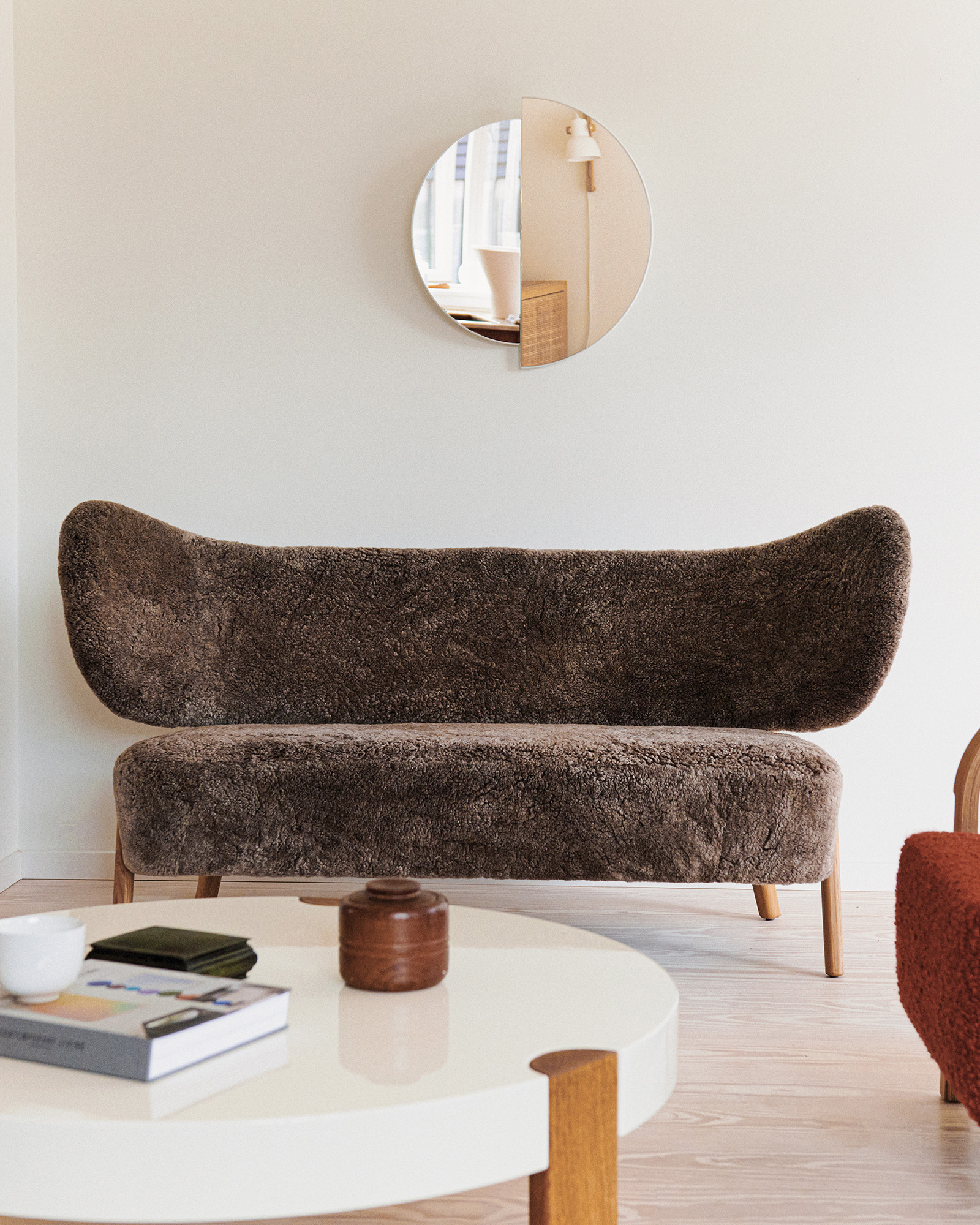 TMBO Sofa in brown sheepskin in front of a round RAE mirror above the FER Coffee Table