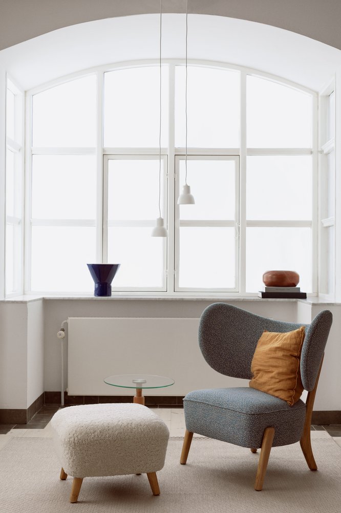 Two white 16PLUS Pendants above a lounge chair and pouf in front of an arched window
