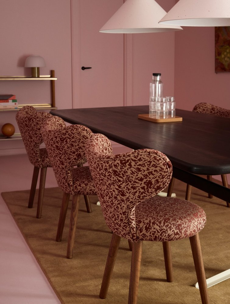 WNG Chairs in red patterned upholstery at a dark table in a pink-walled dining room
