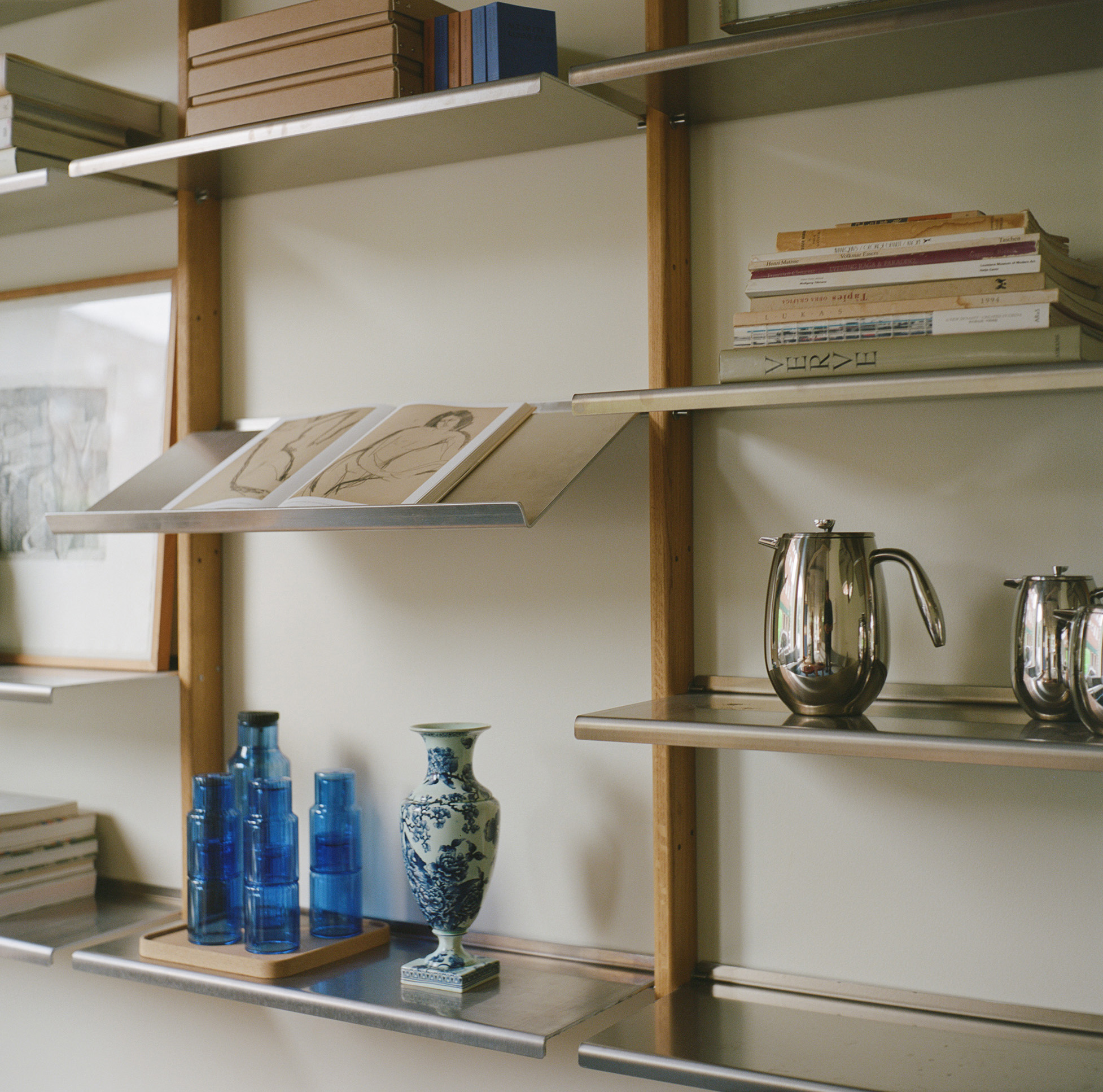 MOD Shelving System in oak and aluminium with blue glass bottles, a floral vase and a steel jug