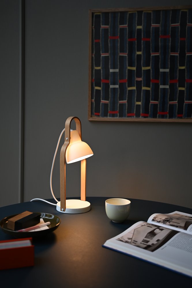 16PLUS Table Lamp on a dark table with a cup and open magazine