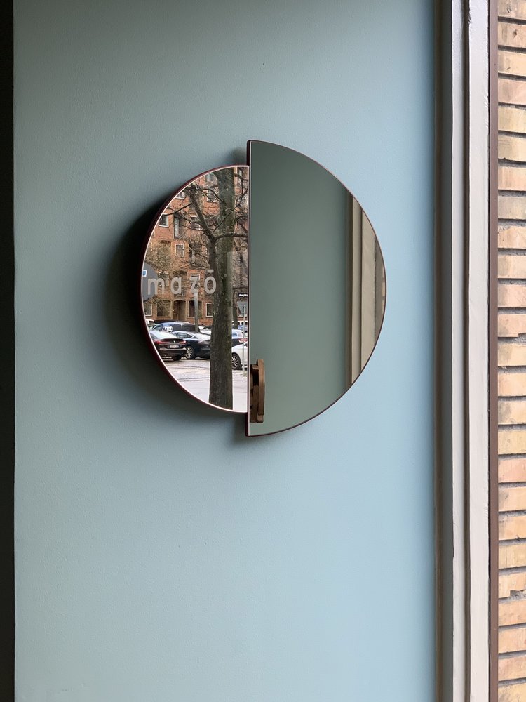 RAE Mirror O60 mounted on a light blue wall by the mazo storefront window