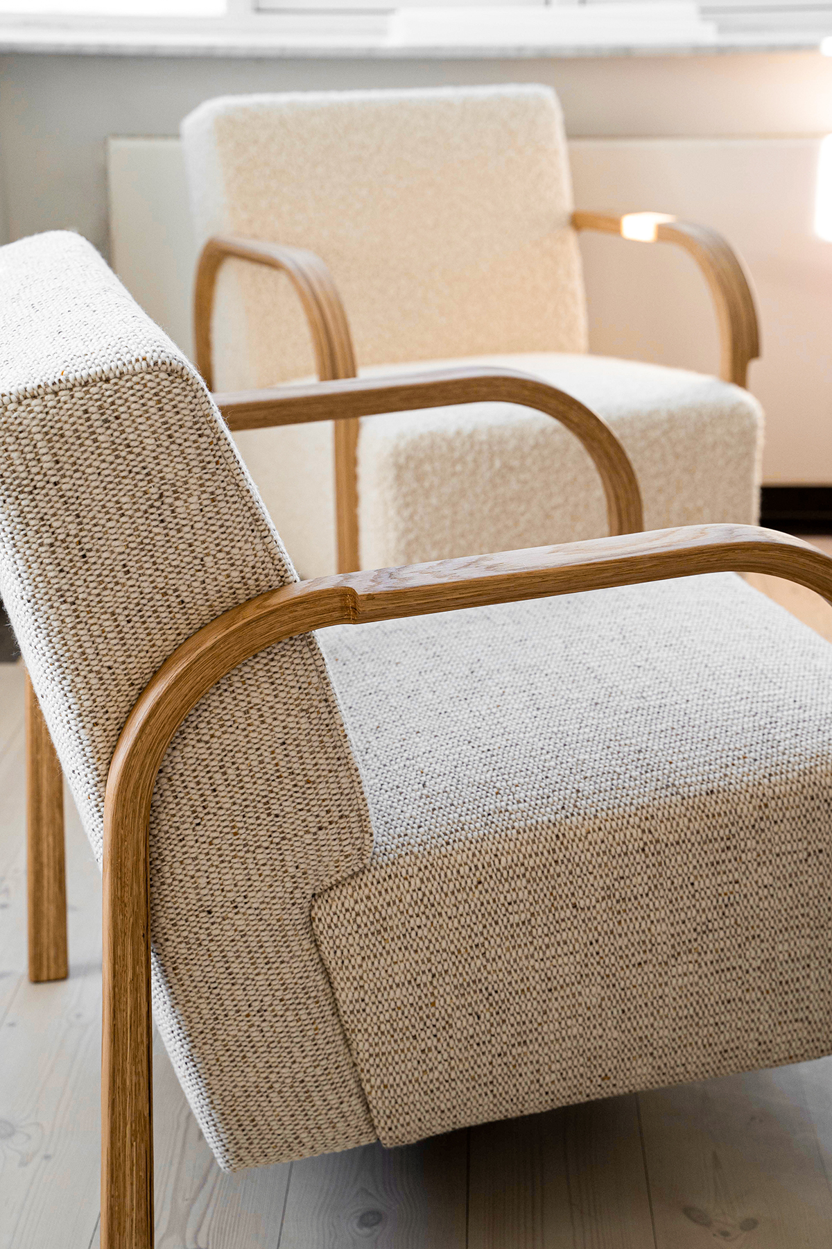 Detail of the Arch Lounge Chair in cream bouclé with curved oak arms