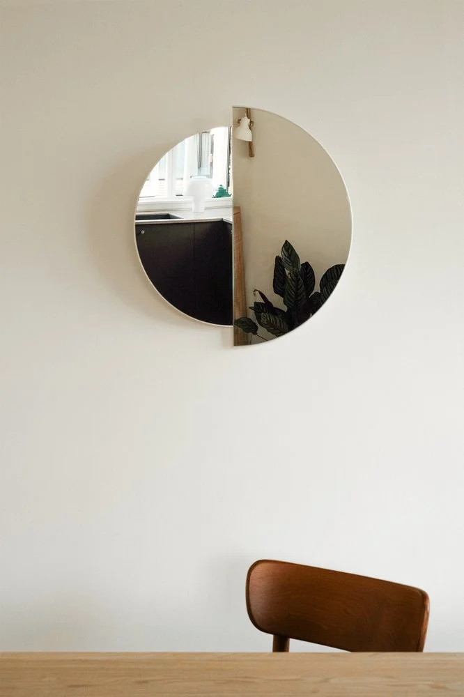 RAE Mirror O60 on a white wall above a wooden chair