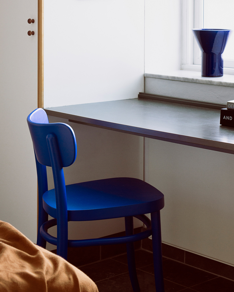 Blue MZO Chair at a desk by an open window with a blue vase on the sill