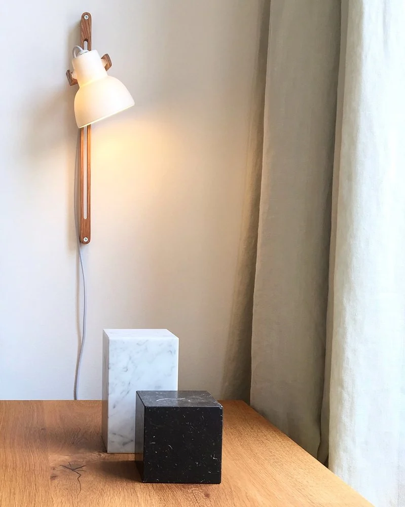 16PLUS Wall Lamp Adjustable above marble cubes on an oak table