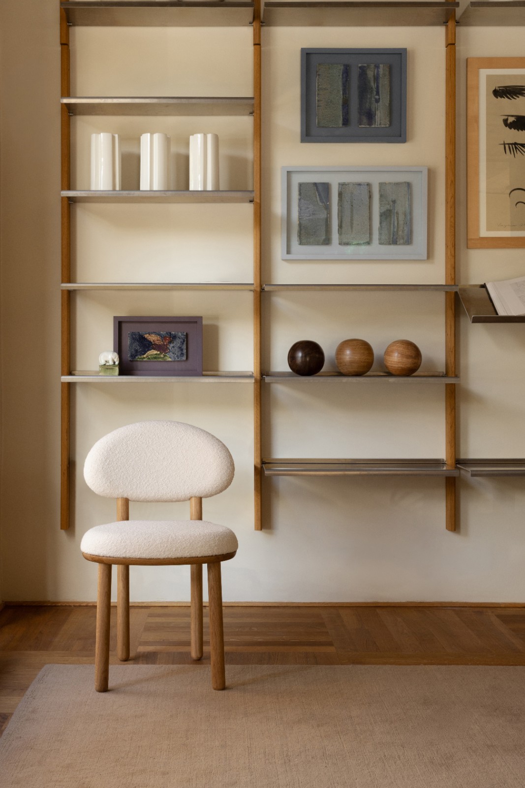 MOD Shelving System in oak and aluminium with ceramics and framed art, a bouclé chair in front