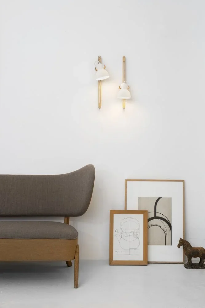 Two 16PLUS Wall Lamps Adjustable above a grey sofa and framed drawings